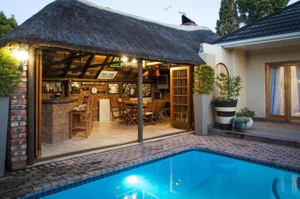 Outdoor swimming pool and thatched lapa at Guest House Ascot Place
